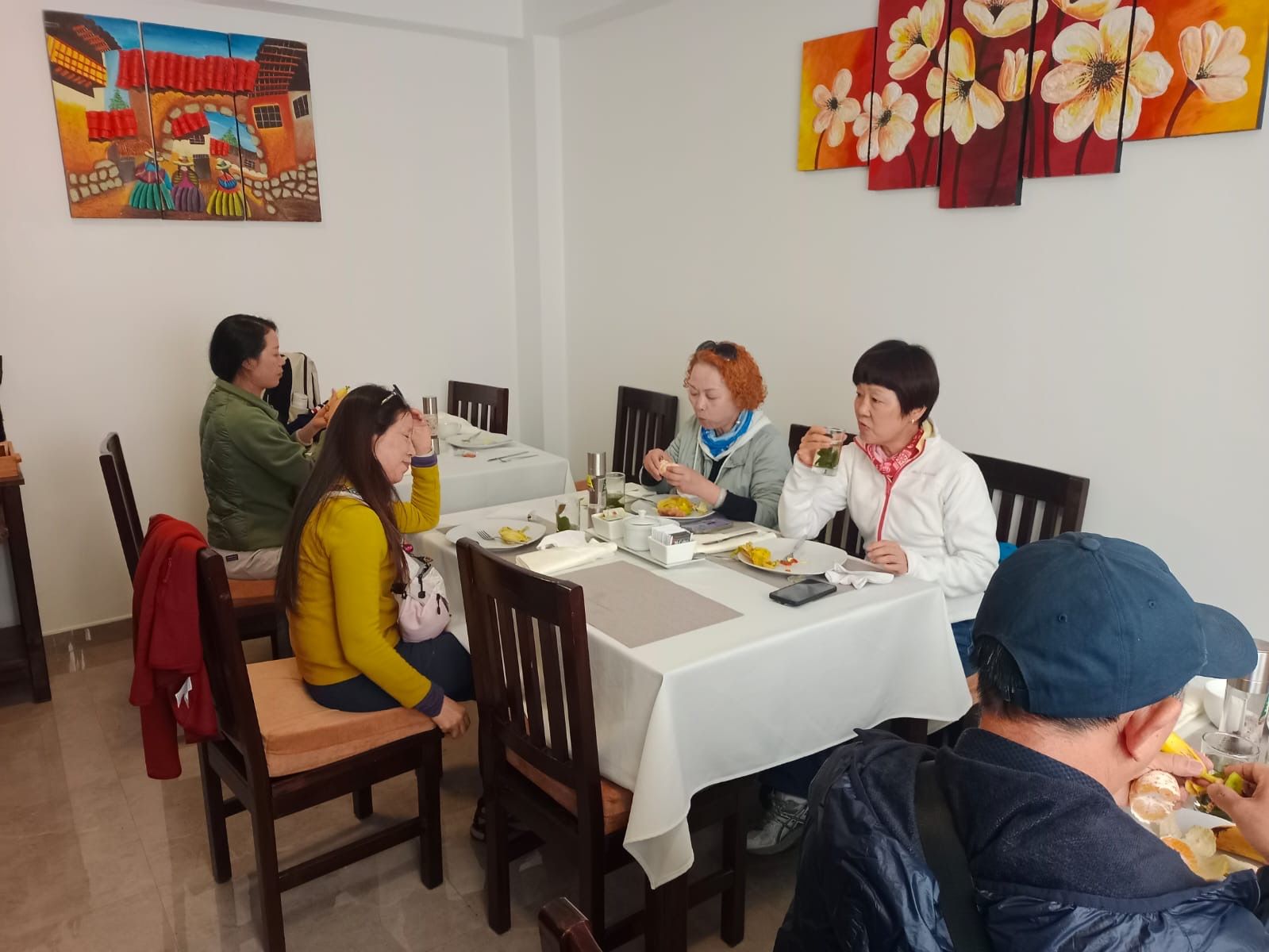 A group of people dining at a table with a white tablecloth, surrounded by chairs.