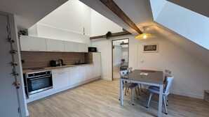Una cocina moderna con armarios blancos, encimera de madera y un comedor con mesa y sillas.