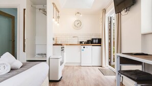 Una habitación compacta con cama, kitchenette pequeña, comedor y vistas al exterior.