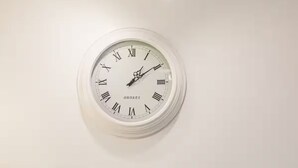 Una cocina con azulejos blancos tipo metro, un lavamanos de acero inoxidable, un reloj y electrodomésticos modernos.