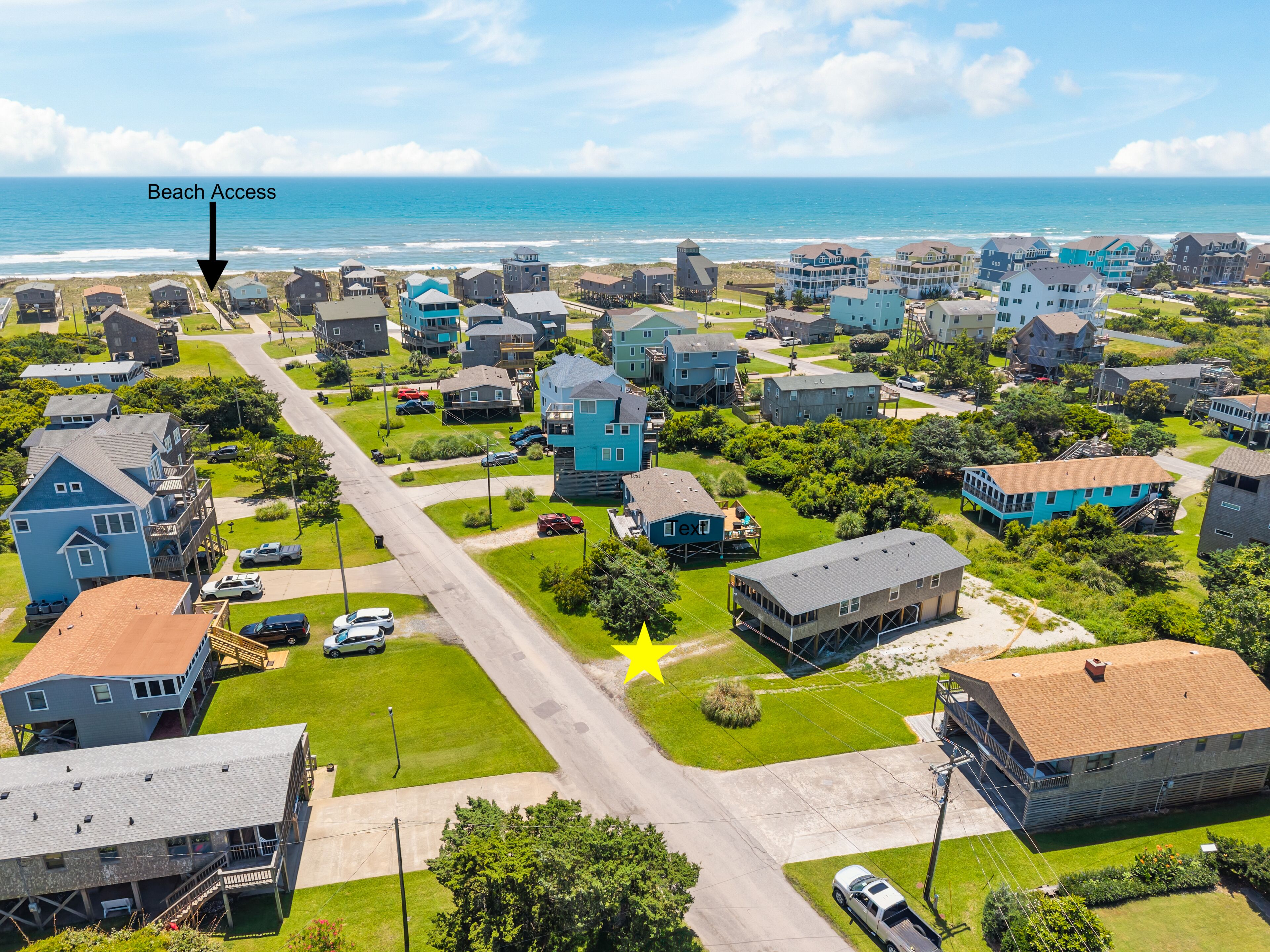 A coastal residential area with houses, a beach access point, and a star-rated establishment.