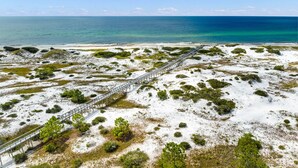 An aerial view of a coastal area with a wooden boardwalk leading to the beach.
