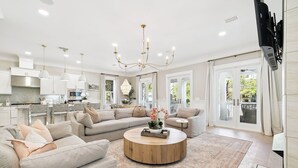 A spacious living area with a large L-shaped sofa, a round coffee table, and a chandelier.