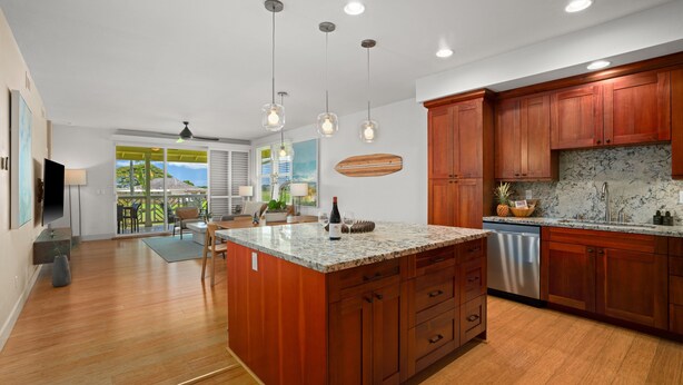 A modern kitchen with wooden cabinets, granite countertops, and pendant lighting.