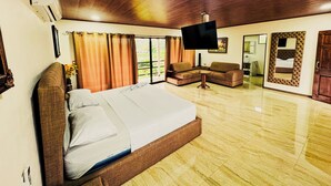 A spacious room with a large bed, a sofa, a television, and a sliding door leading to a balcony. - Los Angeles Hotel & Resort  (Parrita)