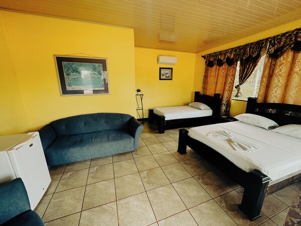 Una habitación con dos camas, un sofá y una pequeña mesa.