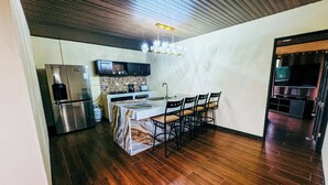 A modern kitchen with a marble island, dark wooden flooring, and a built-in oven. - Los Angeles Hotel & Resort  (Parrita)