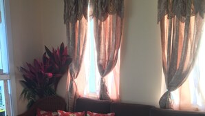 A living room with a dark brown sofa, red patterned cushions, and a large potted plant. - 3-bedroom house in the Nature Isle, Canefield, Dominica (Canefield)