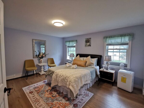 Une chambre à coucher comprenant un lit, une chaise, une table de chevet, une commode et un radiateur.