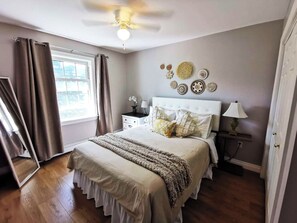 Une chambre à coucher comprenant un lit, des tables de chevet, un ventilateur de plafond et des éléments de décoration murale.