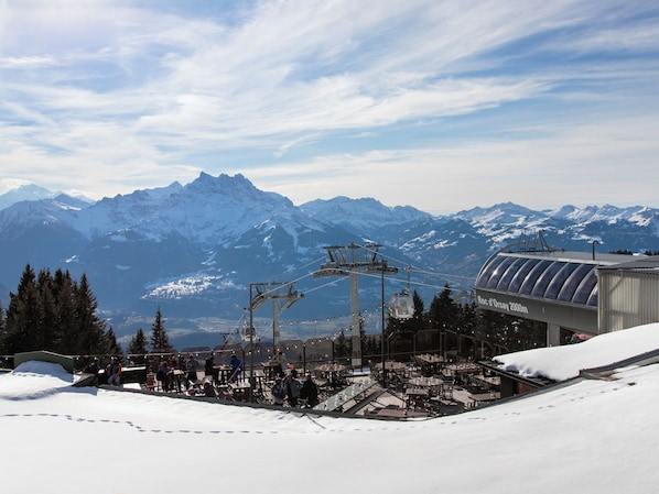 A ski resort with a chairlift, snow-covered mountains, and a restaurant area.