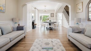A spacious living room with a central dining area, a staircase, and a view of the outdoors. - Stylish Townhouse Annexe Cheltenham (Cheltenham)