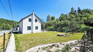 Uma casa moderna com fachada branca, varanda coberta e gramado bem cuidado.