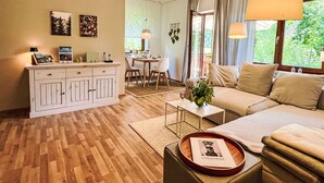 A modern living room with a sofa, a dining table, and a kitchen area.