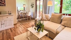 A cozy living room with a sofa, a coffee table, and a dining area with chairs and a table.
