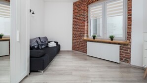 A modern room with a black sofa, a white radiator, and a brick wall.