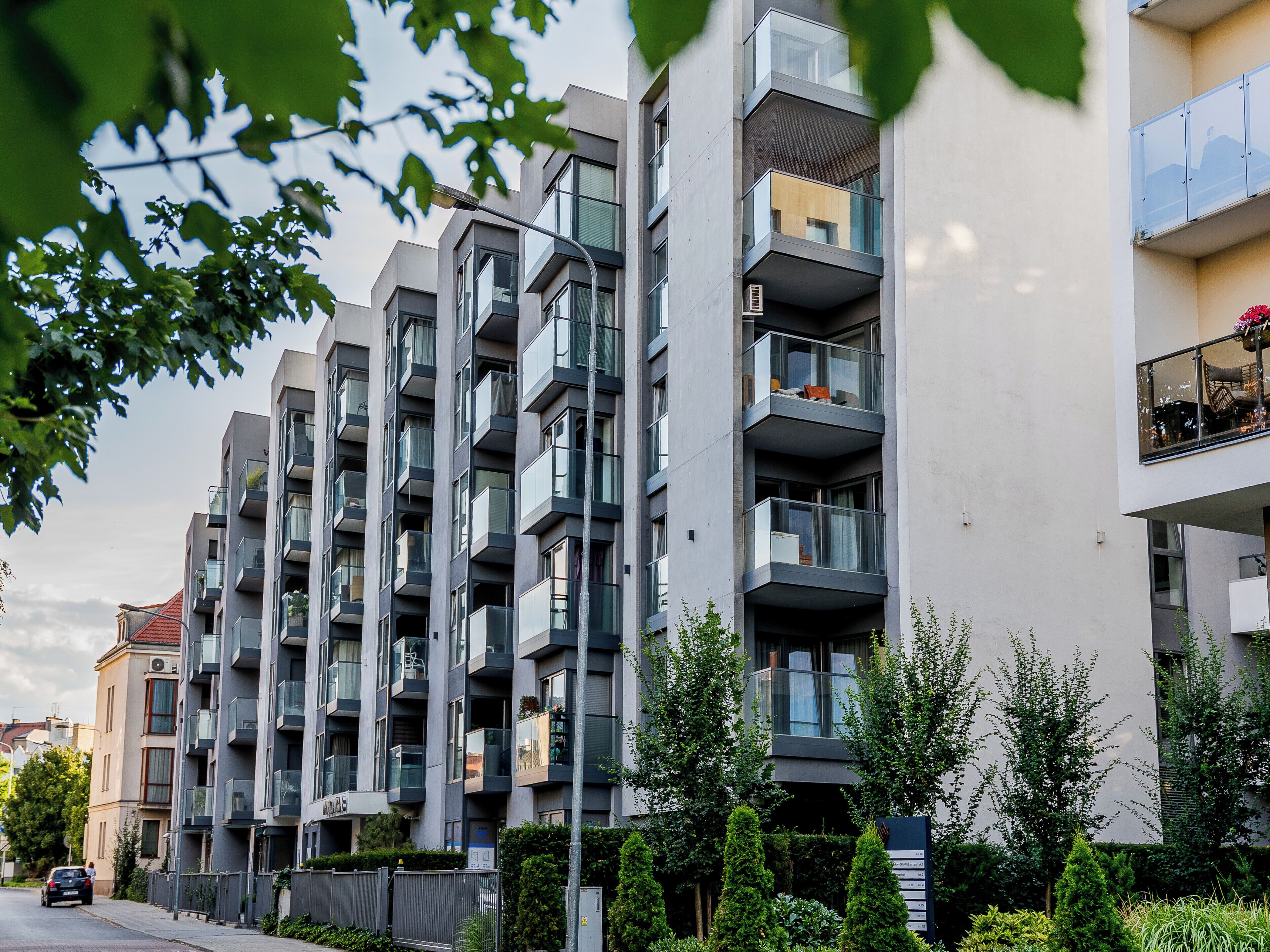 Een modern meerlaags woongebouw met balkons, een hekpoort en een straatbeeld.