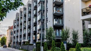 Ein modernes, mehrgeschossiges Wohngebäude mit Balkonen, einem verschlossenen Eingang und Blick auf die Straße.