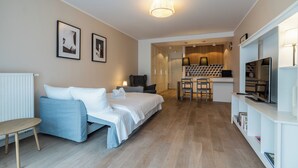 Ein kleines Hotelzimmer mit Bett, Schreibtisch und einer Küchenzeile.