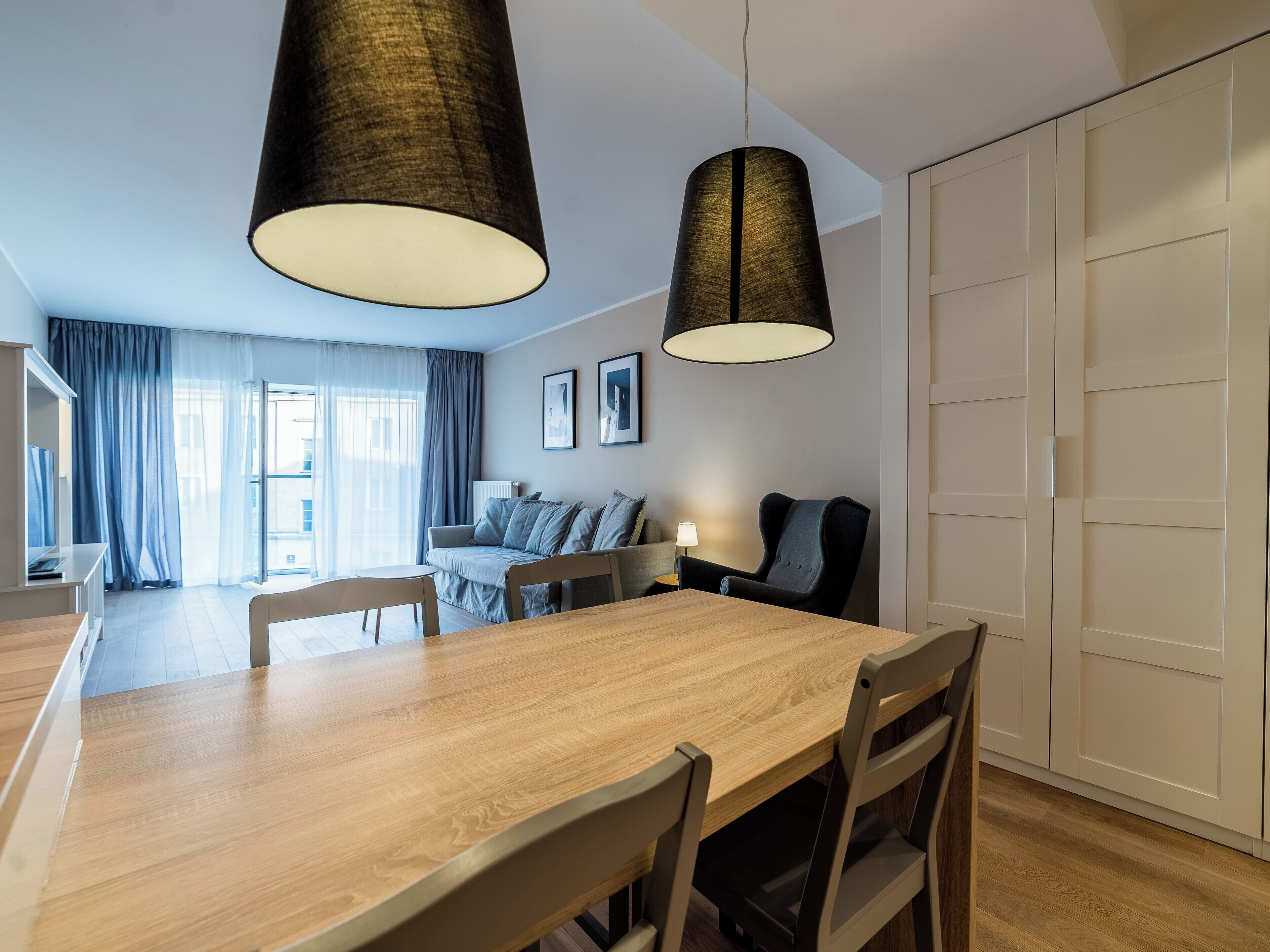Ett modernt matområde med ett träbord och stolar, en soffa och en lampa.