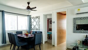A modern dining area with a table set for four, a ceiling fan, and a decorative wall piece. - SeaView FrontBeach Apartments  (Cartagena)