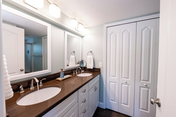 Un bagno con due lavandini, uno specchio grande e una porta con maniglia.