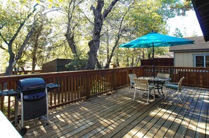 A wooden deck with a grill, chairs, and a table under a blue umbrella. - Sunrise on Sunset (Sugarloaf)