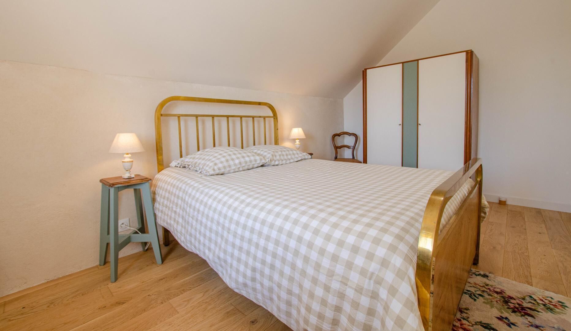 Ein Schlafzimmer mit einem Bett, zwei Nachttischen, einem Schrank und einem Stuhl.
