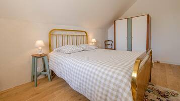 A bedroom with a bed, two bedside tables, a nightstand, a chair, and a wardrobe.