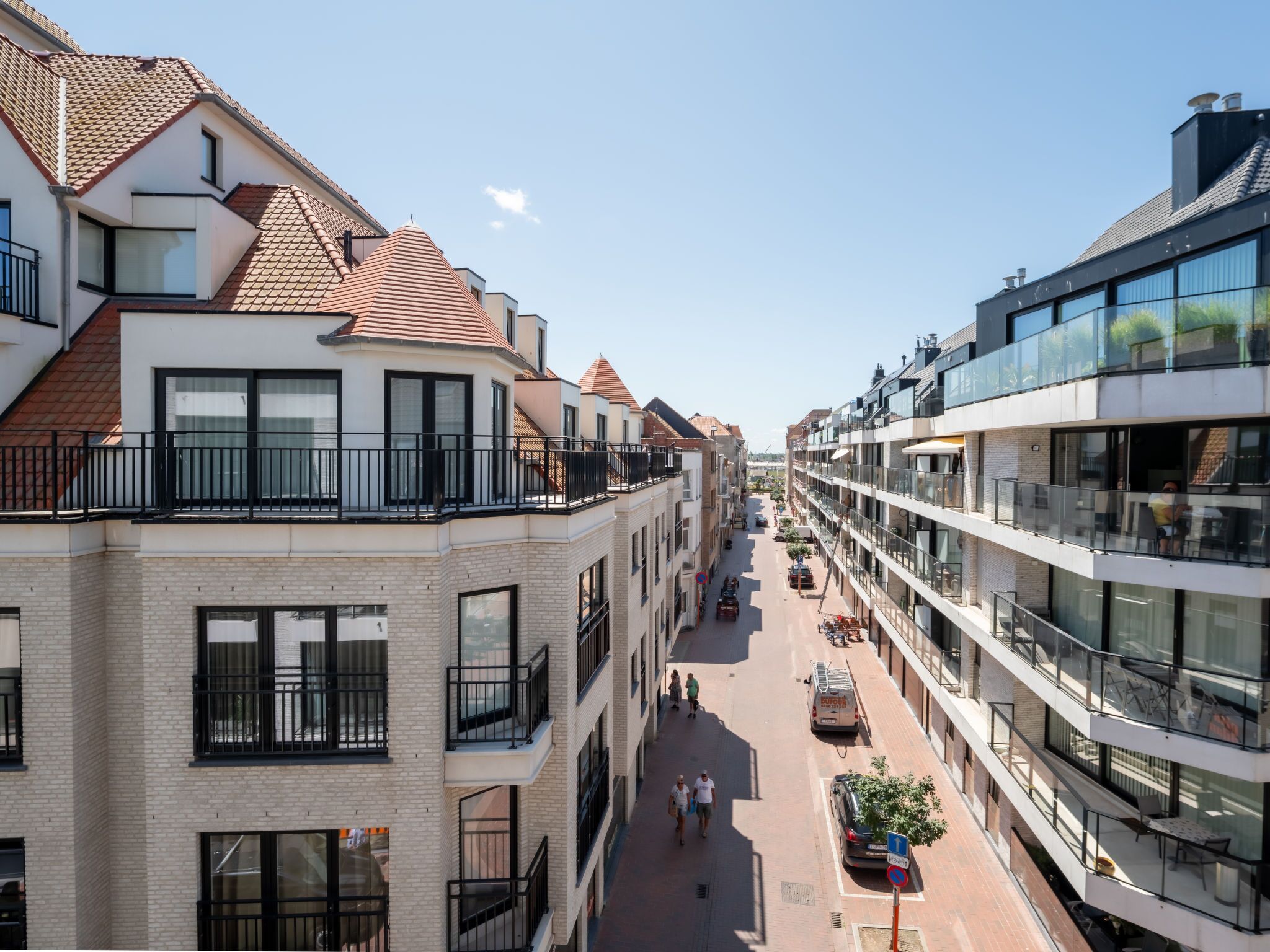 Ein mehrgeschossiges Gebäude mit Balkonen, großen Fenstern und einer Fußgängerstraße.