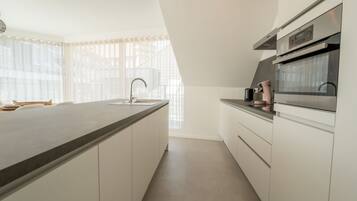 Een koelkast, een microgolfoven, een oven, kookgerei, borden en bestek