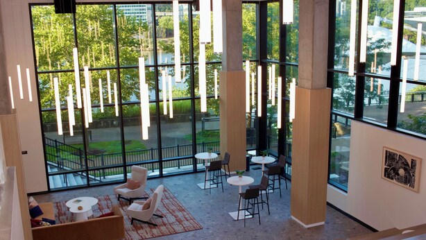 Um espaço amplo e interno, com grandes janelas, móveis modernos e luminárias pendentes.