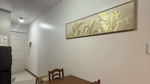 A dining area with a wooden table and chairs, a ceiling fan, and a wall-mounted artwork. -  1- BEDROOM MARTEL 603 VERDON PARC (Davao City)