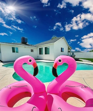 Una piscina con dos flotadores de flamenco rosados.