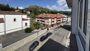 Une vue de rue avec des bâtiments, des voitures et une montagne en arrière-plan.