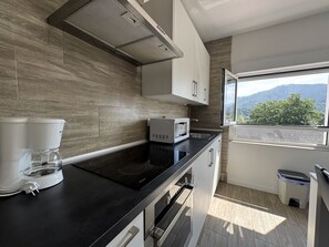 Geladeira, fogão, talheres/pratos/utensílios de cozinha, mesas de jantar