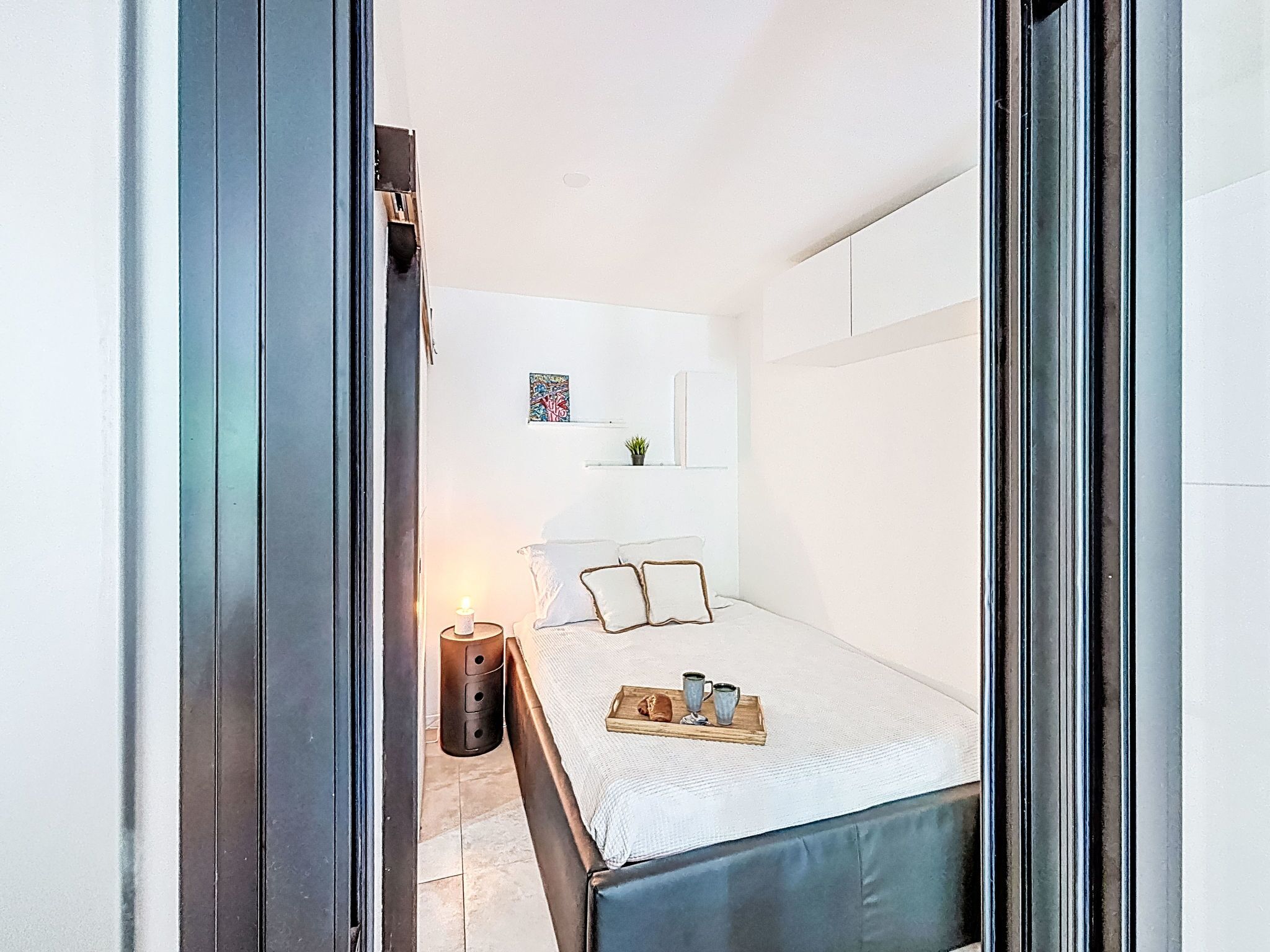 Una camera da letto moderna con un letto, un comodino e una piccola pianta in vaso.