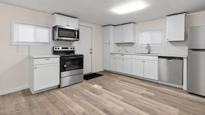 Una cocina moderna con armarios blancos, electrodomésticos de acero inoxidable y piso de madera.
