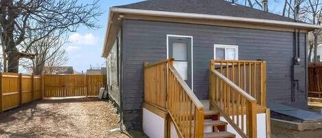A small single-story house with a wooden staircase leading to a front door.