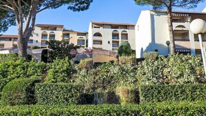 A hotel with multiple balconies, a courtyard with greenery, and a clear blue sky. - La Gaillarde by Interhome (Les Issambres)