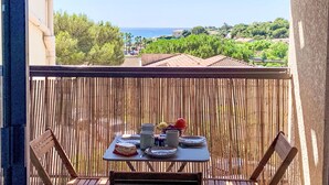 A balcony with a table set for two, overlooking a coastal landscape with houses and greenery. - La Gaillarde by Interhome (Les Issambres)