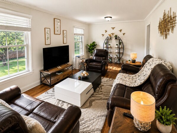 A living room with a flat-screen TV, leather sofas, a coffee table, and a fireplace.