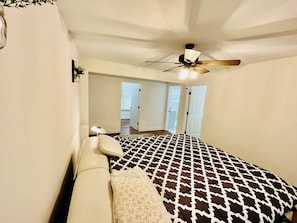 Une chambre à coucher avec un lit, un ventilateur de plafond et une vue sur l’extérieur.