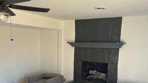 Un salon doté d’une cheminée, d’un ventilateur de plafond et d’un canapé d’angle.