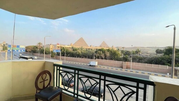 Un balcone con vista su una strada, una piramide e alcuni edifici.