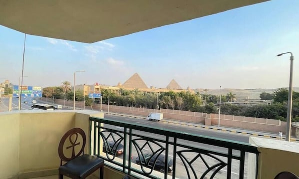 A balcony with a view of the pyramids, a road with vehicles, and a street sign. - Stay inn pyramids  (Giza)