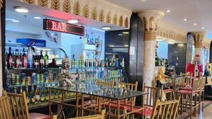 Un'area bar con un frigorifero Pepsi, diverse bottiglie e sedie di legno.