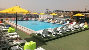 Una piscina con lettini e ombrelloni, circondata da un prato verde.