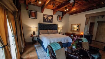A bedroom with a large bed, two bedside tables, a dresser, a mirror, and a wooden ceiling.