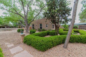 A house with a well-maintained garden, including hedges and trees. - Santuario Grande (Los Ranchos de Albuquerque)